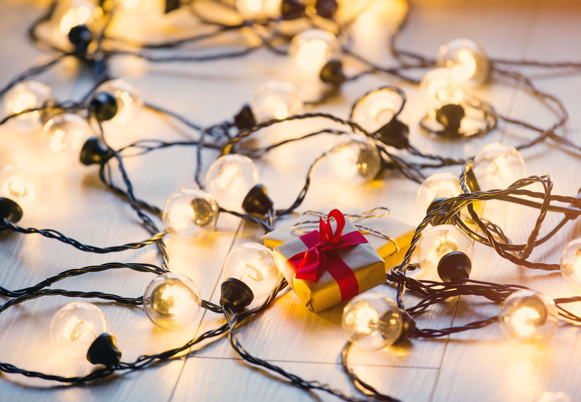 Christmas Gift And Fairy Lights On White Tile